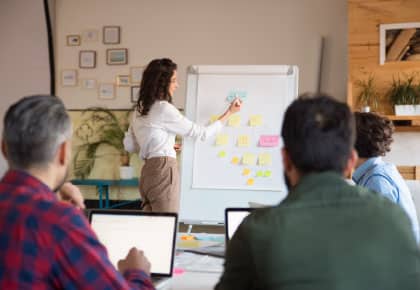 Woman standing at a flipchart, delivering training to a group of people